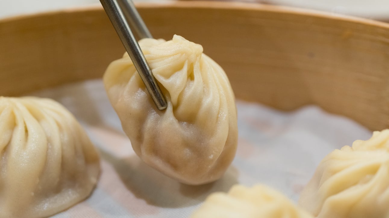 Chopsticks Taking a Pork Xiaolongbao Dumpling in a Bamboo Basket